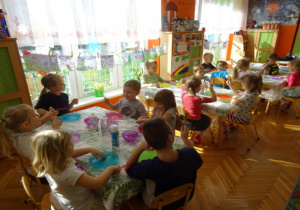 Dzieci przygotowują się przy stolikach do zajęć.